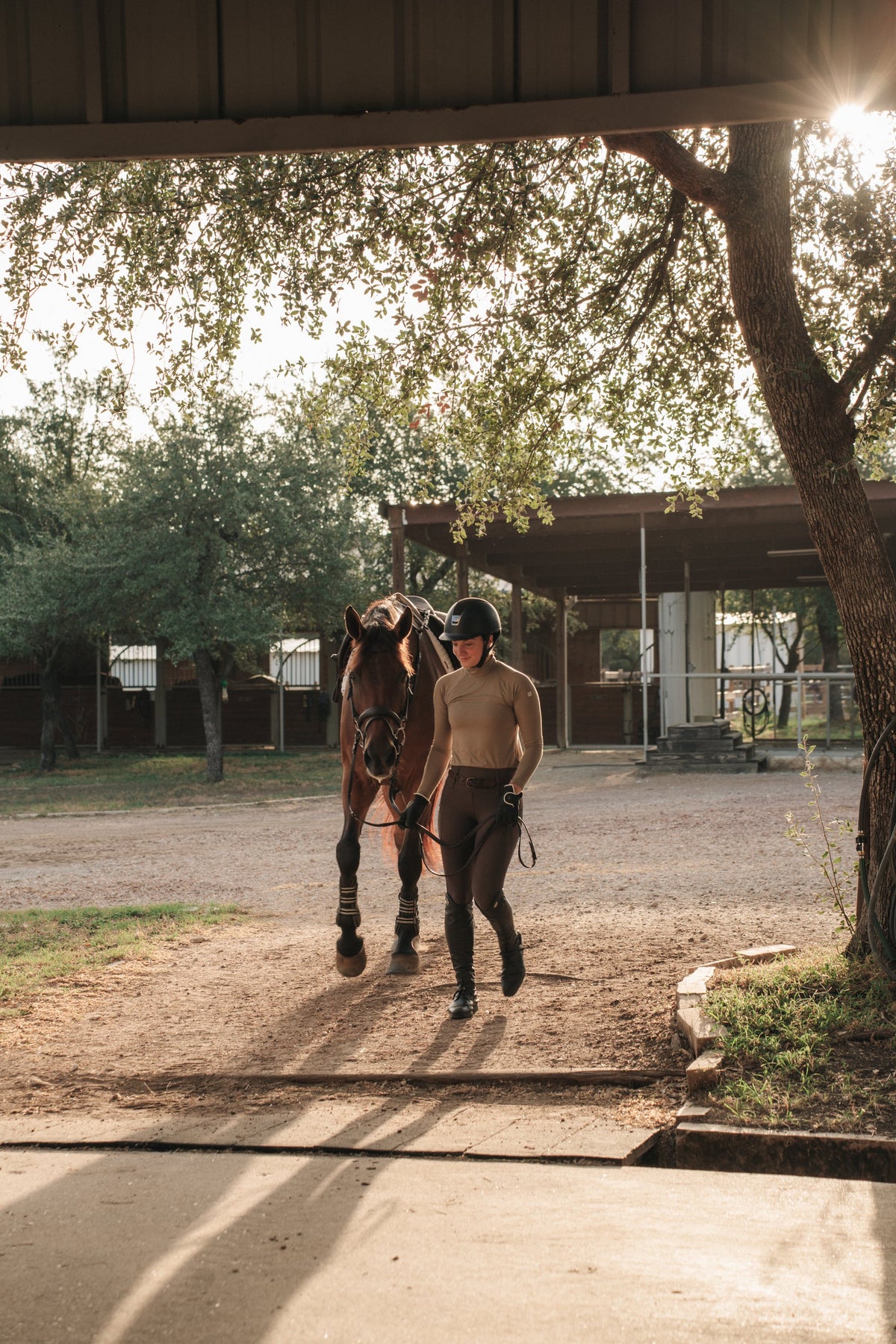 Rider in the khaki Mia Mock Neck walking a horse out of the stables