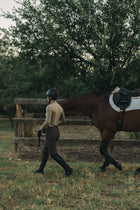 Rider in the khaki Mia Mock Neck leading a horse past the fence