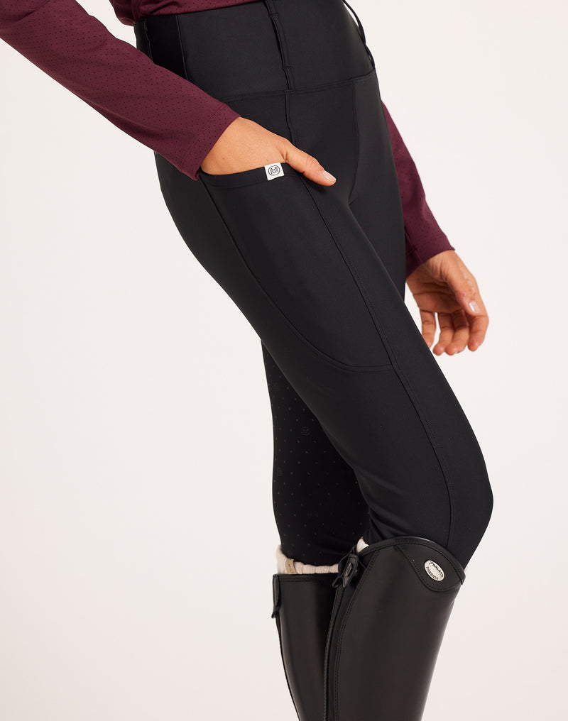 Women's high-rise knee grip black equestrian breeches for horse riding, designed with performance stretch fabric, supportive waistband, flattering seam lines, and functional pockets. Versatile riding pants for schooling, casual rides, barn days, and everyday equestrian wear.