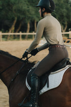 Rider wearing the Mia Mock Neck in khaki, cantering in a sand arena