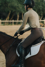Rider wearing the Mia Mock Neck in khaki, cantering in a sand arena